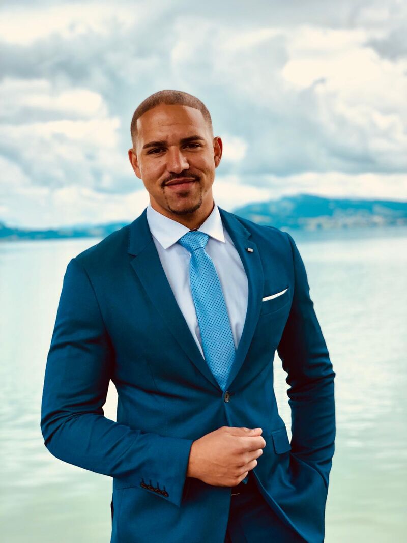 Antoine Bracmort en traje azul frente a un lago